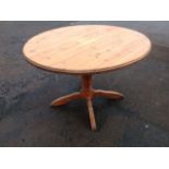 A circular pine breakfast table, the moulded top raised on ring-turned column with four shaped