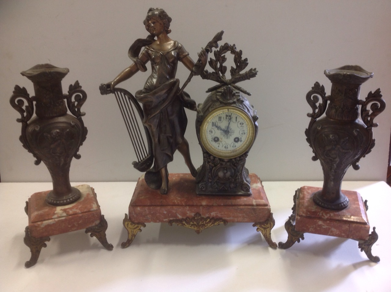 An art nouveau French clock garniture, the central timepiece with maiden holding harp aside a clock,
