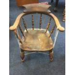 A nineteenth century elm captains chair, the rounded back on spindles above a solid seat, raised