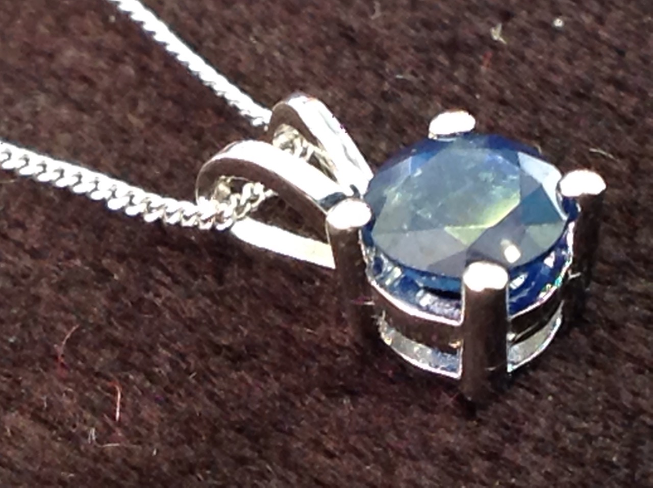 An 18ct white gold single stone sapphire pendant, the claw set stone on a fine chain weighing