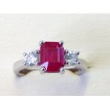 An 18ct emerald cut ruby & diamond ring, the claw set ruby of nearly two carats, flanked by two