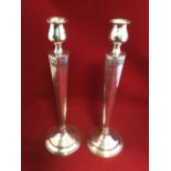 A pair of sterling silver candlesticks, with urn shaped candleholders on a hexagonal tapering