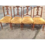 A set of four Victorian carved walnut dining chairs, the scroll carved back rails above pierced