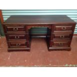 A mahogany kneehole desk, with rectangular top above shaped apron and two pedestals, each having