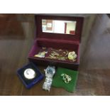 A maroon leather jewellery box containing a Cartier style wristwatch, a spray brooch, chains, an