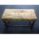 A nineteenth century rectangular stool, with needlework tapestry upholstered seat raised on baluster