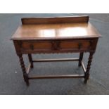 An oak side table with shaped upstand on rectangular moulded top, having two panelled frieze drawers