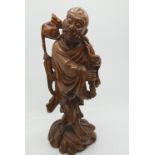 A nineteenth century Chinese carved wood figure of an oriental man, holding shoe and stuff, with