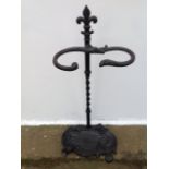 A cast iron stickstand, having fleur-de-lils finial above scrolled holder on a twisted column,