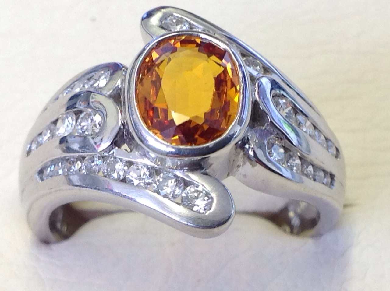 An 18ct gold oval yellow sapphire & diamond crossover ring, the central bezel set stone of 1.42