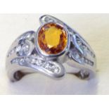 An 18ct gold oval yellow sapphire & diamond crossover ring, the central bezel set stone of 1.42