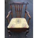 A Georgian mahogany open armchair, with scroll carved back rail above a wide pierced splat and crook