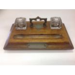 An Edwardian oak desk tidy, the moulded rectangular stand on bun feet, fitted with twin glass