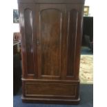 A Victorian mahogany wardrobe, with arched door and panels enclosing hanging space, having long