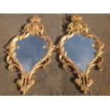 A pair of carved giltwood mirrors, with pierced acanthus scrolled shaped frames surmounted by