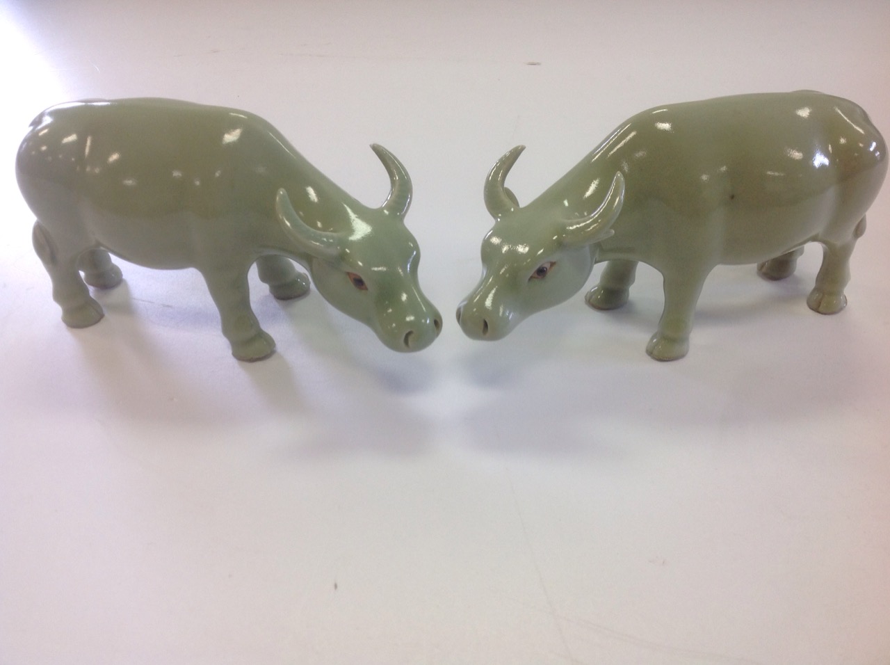 A pair of Chinese oxen, the animals with celadon glaze having black eyes and shaped horns. (6.5in)