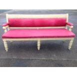 A Victorian settle, the painted reeded seat with scrolled arms supported on columns, upholstered