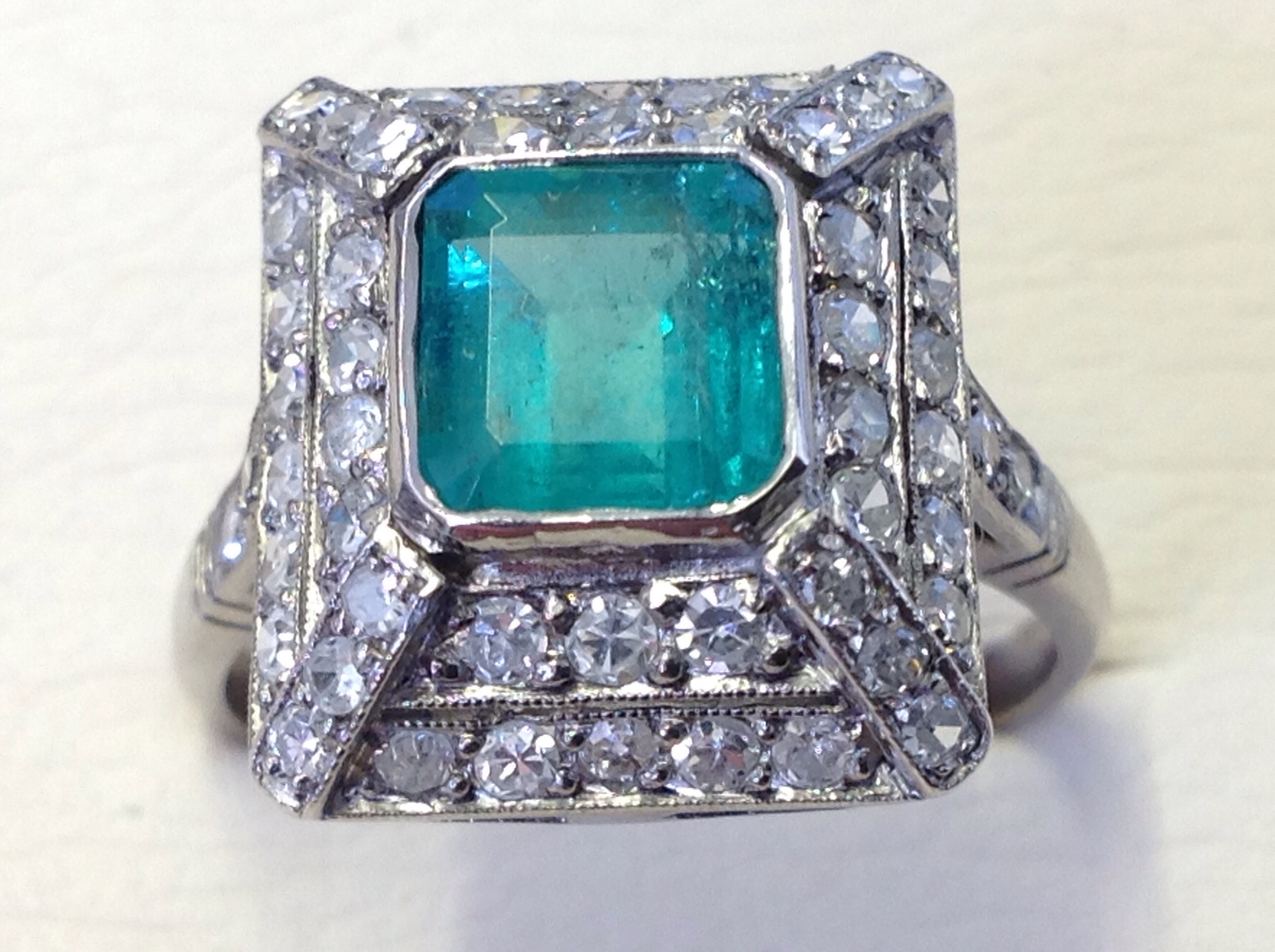 A square emerald & diamond pyramid shaped ring, the Columbian emerald of over 1.5 carats, framed