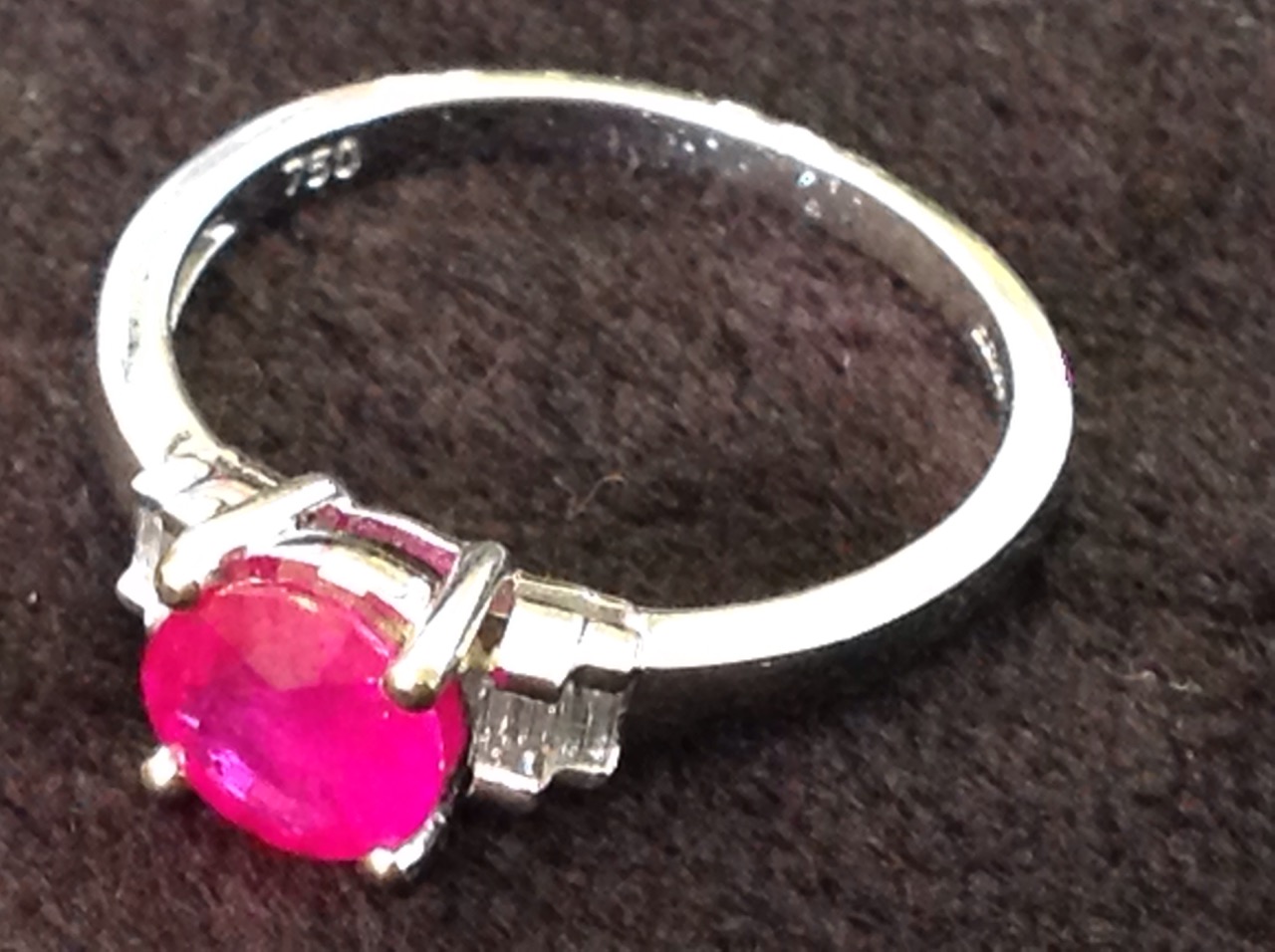 An 18ct gold ruby & diamond ring, the circular claw set ruby weighing three-quarters of a carat,