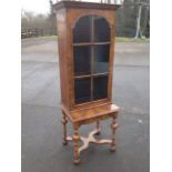 A Queen Anne style walnut cabinet on stand, with moulded cornice above arched astragal glazed