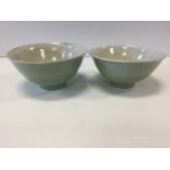 A pair of early Chinese celadon glazed bowls, raised on tubular bases, unmarked and one