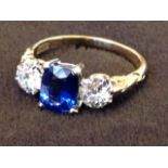 An 18ct gold sapphire & diamond three stone ring, the claw set rectangular sapphire of 1.35