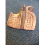 A hardwood carved stirrup dated 1890, decorated with panels of roundel shells, with cast iron and