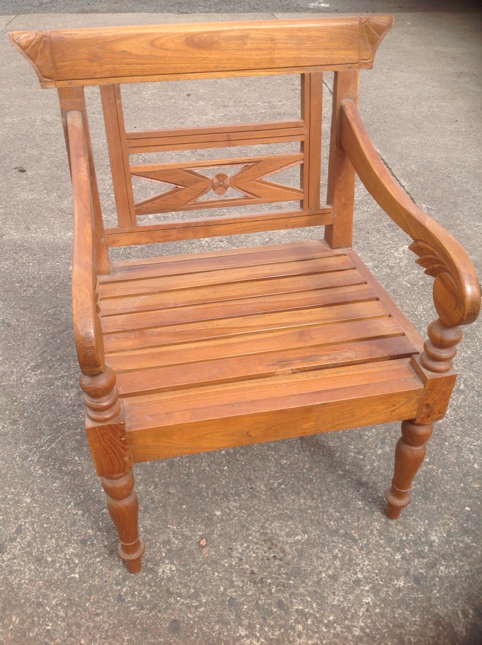 A carved hardwood armchair, the back with floral pierced panel, having leaf carved arms on turned