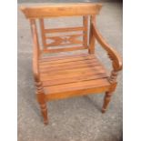 A carved hardwood armchair, the back with floral pierced panel, having leaf carved arms on turned