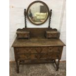 An oak dressing table with circular mirror on barleytwist columns above two small drawers, the chest