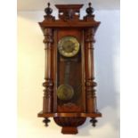 A Victorian walnut Vienna wallclock, the crest with turned finials flanking masque above an arched