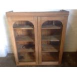 A Victorian glazed mahogany cupboard, with arched doors enclosing adjustable shelves.