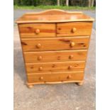 A reproduction pine chest of drawers, the serpentine moulded top above two short and four long