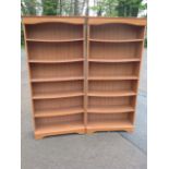 A pair of pine style open bookcases, having moulded cornices above arched aprons, each with five