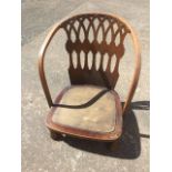 A low nursing style chair, the bowed back with gothic shaped pierced fretwork panel, raised on