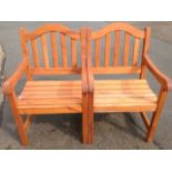 A pair of hardwood garden armchairs, with arched slatbacks above slatted seats framed by rounded