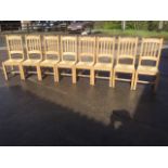 A set of eight beech dowel-jointed dining chairs, the arched slatbacks above rush seats, raised on
