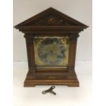 An Edwardian walnut cased mantleclock of architectural form, the pediment with scrolled carving