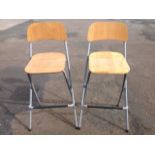 A pair of folding high chair stools, with shaped oak backs & seats, on tubular metal frames with
