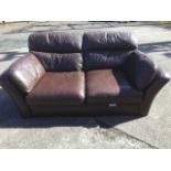 A brown leather two-seater sofa with flared arms and loose cushions.