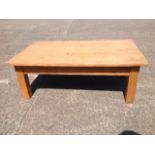 A pine coffee table, having rectangular top supported on square column legs.