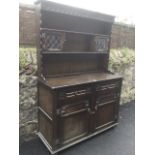 An oak dresser, the back with carved apron and waved uprights framing leaded glass cupboards and