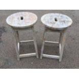 A pair of circular hardwood stools, the seats with handholes, supported on square angled column legs