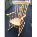 A beech fiddleback rocking chair, with pierced splat framed by slats, having shaped arms supported