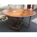 An oval oak dining table, the moulded top with two drop flaps supported on gates, raised on