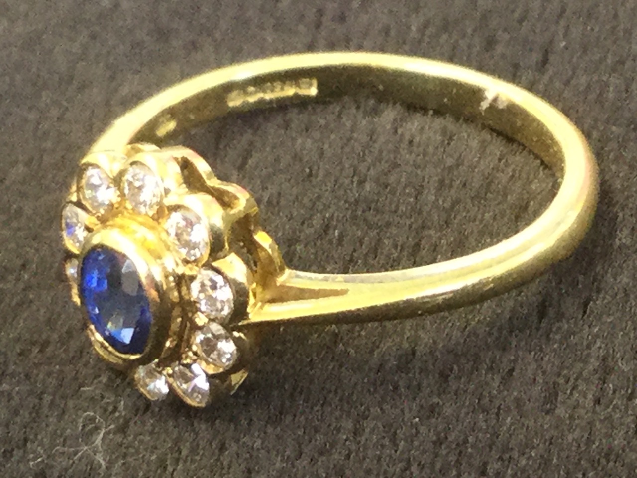 A 18ct yellow gold sapphire & diamond cluster ring, the oval bezel set sapphire framed by a border - Image 2 of 3