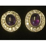 A pair of purple sapphire & diamond ear studs, the oval cabochon sapphires each framed by sixteen