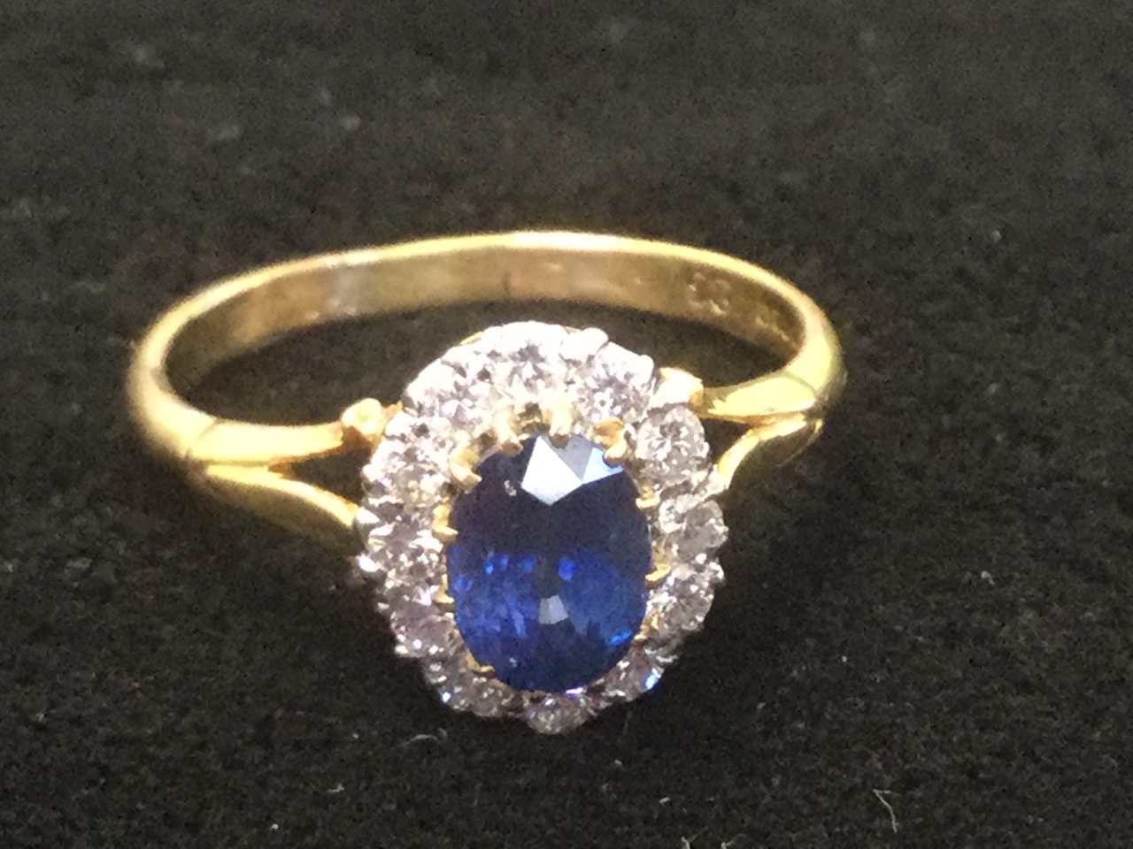 A sapphire & diamond ring, the oval claw set sapphire of over a carat, framed by twelve diamonds - Image 3 of 3