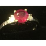 An 18ct gold ruby & diamond ring, the circular claw set ruby weighing three-quarters of a carat,