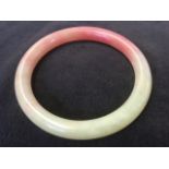 A carved jade bangle, the ring in rose and mutton colour. (3in)